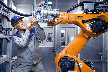 A Leadec employee maintaining a robot in a production area.