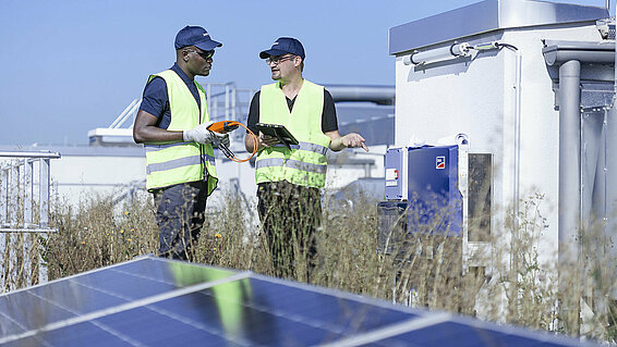 Two Leadec employees on factory roof with photovoltaic panels.