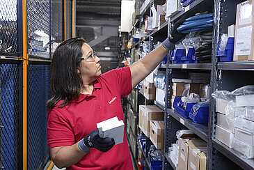 Female Leadec employee restocks inventory of spare parts in a warehouse.