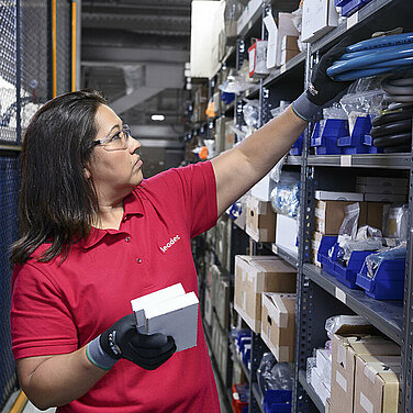 Female Leadec employee restocks inventory of spare parts in a warehouse.