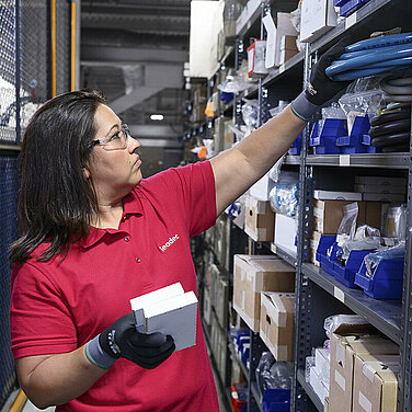 Female Leadec employee restocks inventory of spare parts in a warehouse.